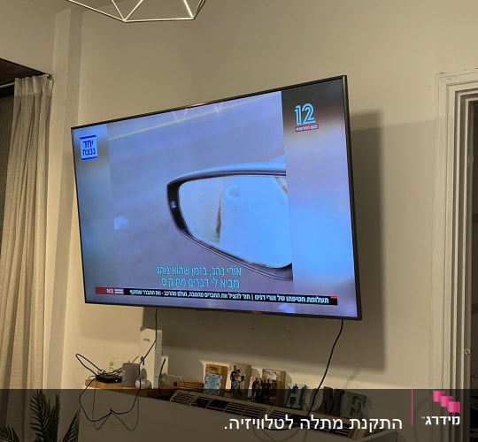 טלוויזיה תלויה על הקיר עם כבלים חשמליים גלויים